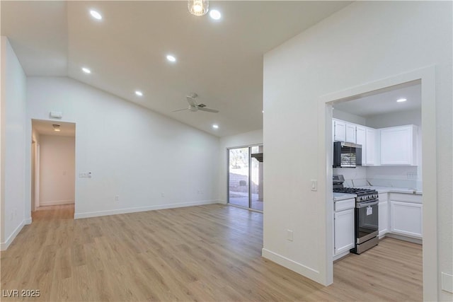 kitchen featuring white cabinets, lofted ceiling, open floor plan, stainless steel appliances, and light countertops