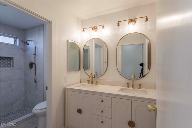 bathroom featuring double vanity, a tile shower, and a sink