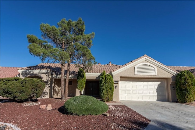 single story home featuring a garage, concrete driveway, a tile roof, and stucco siding