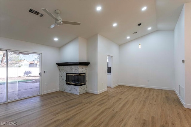 unfurnished living room featuring lofted ceiling, a stone fireplace, visible vents, light wood-style floors, and a ceiling fan