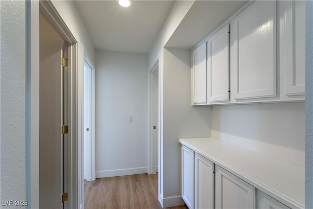 hallway featuring light wood-type flooring and baseboards