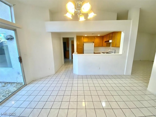 kitchen with light countertops, brown cabinetry, freestanding refrigerator, range, and under cabinet range hood