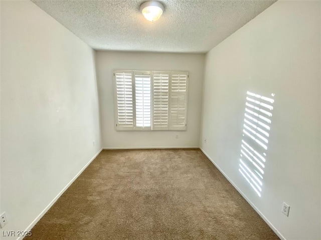 spare room featuring light carpet, baseboards, and a textured ceiling