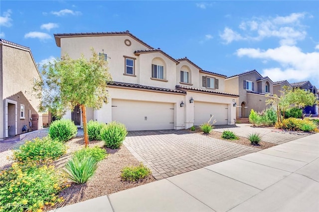 mediterranean / spanish-style home featuring a garage, a tiled roof, decorative driveway, a residential view, and stucco siding