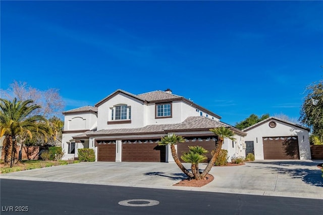 mediterranean / spanish-style home with a garage, concrete driveway, a tiled roof, and stucco siding