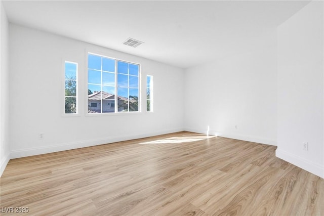 empty room with light wood finished floors, baseboards, and visible vents