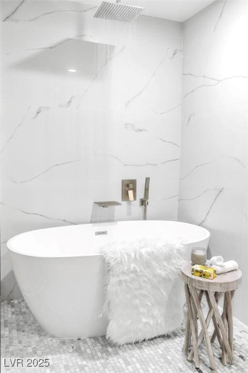 full bath featuring a soaking tub and stone wall