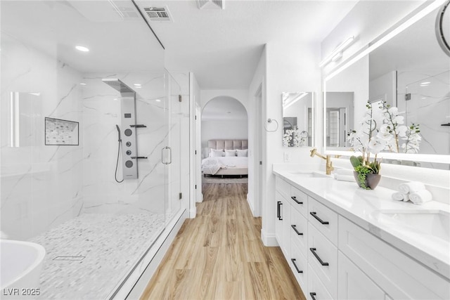 full bath featuring a marble finish shower, visible vents, wood finished floors, ensuite bathroom, and a sink