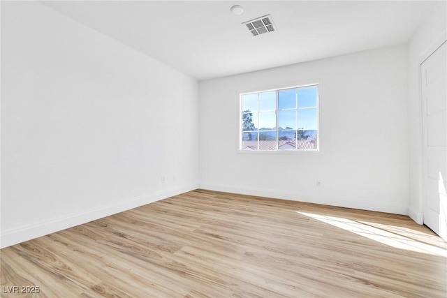 unfurnished room with light wood finished floors, baseboards, and visible vents