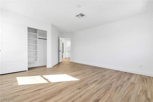 unfurnished bedroom with visible vents, a closet, baseboards, and wood finished floors