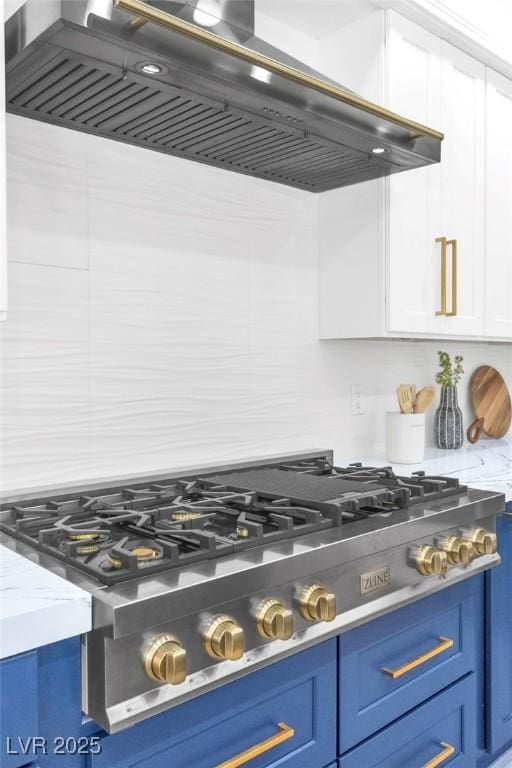 kitchen with white cabinets, light stone countertops, ventilation hood, blue cabinetry, and stainless steel gas cooktop