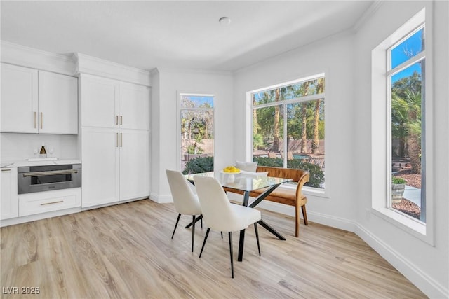 dining room featuring light wood-type flooring, a wealth of natural light, and baseboards