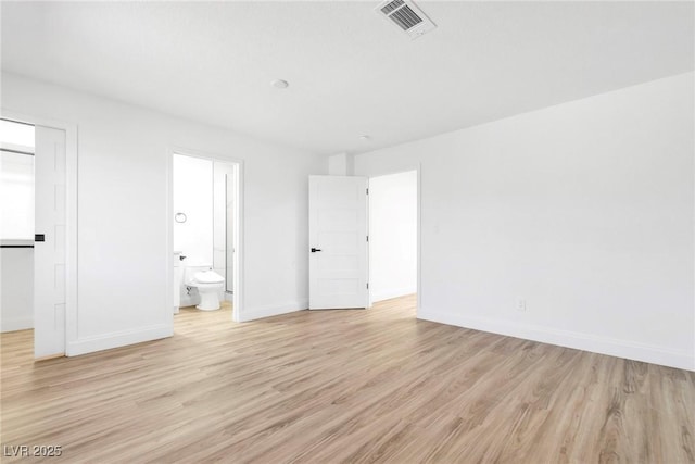 unfurnished bedroom featuring light wood-style floors, visible vents, ensuite bath, and baseboards