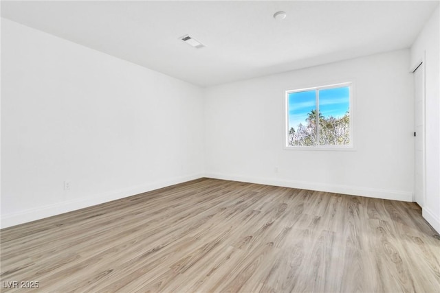 unfurnished room with light wood finished floors, visible vents, and baseboards