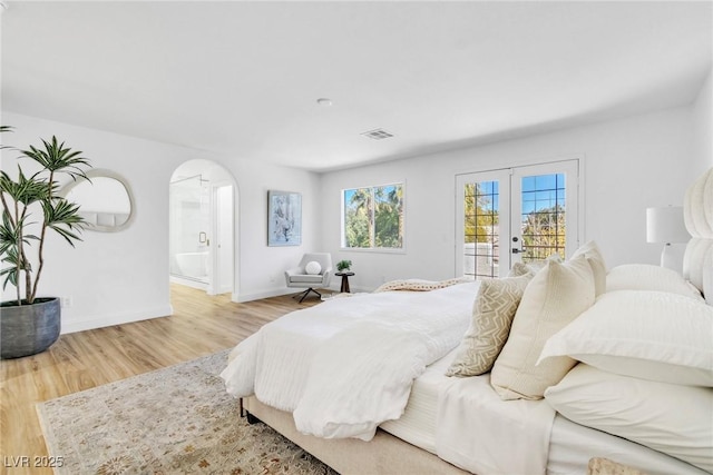 bedroom with arched walkways, wood finished floors, visible vents, access to outside, and french doors