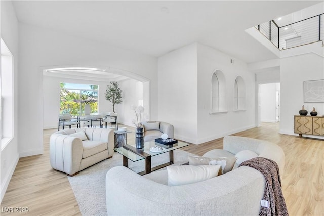 living room featuring light wood-style flooring, arched walkways, and baseboards