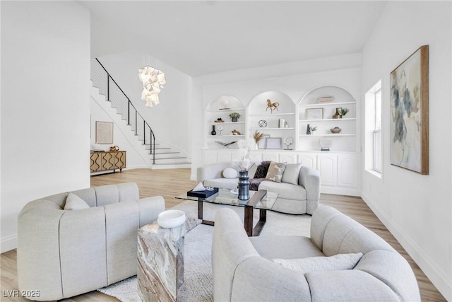 living area with light wood finished floors, baseboards, stairway, and built in features