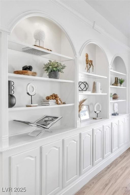 interior details with built in shelves, wood finished floors, and crown molding