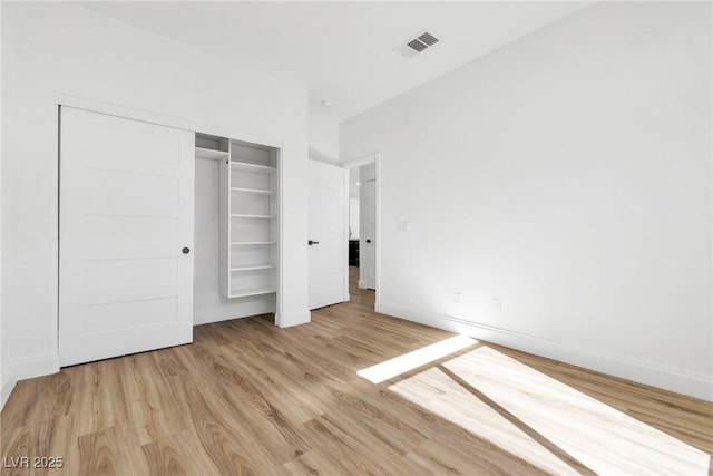 unfurnished bedroom with a closet, visible vents, baseboards, and wood finished floors