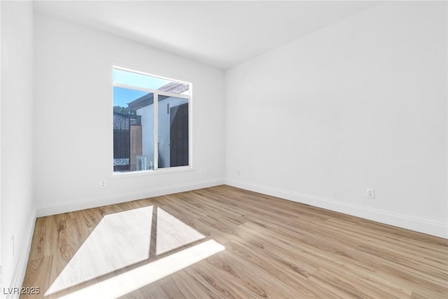 spare room featuring baseboards and wood finished floors