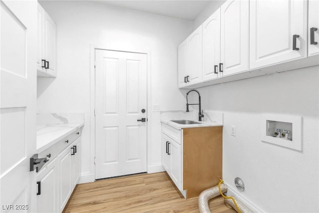 laundry area with light wood finished floors, a sink, cabinet space, and hookup for a washing machine