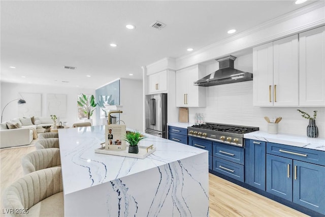 kitchen with open floor plan, wall chimney exhaust hood, appliances with stainless steel finishes, and visible vents