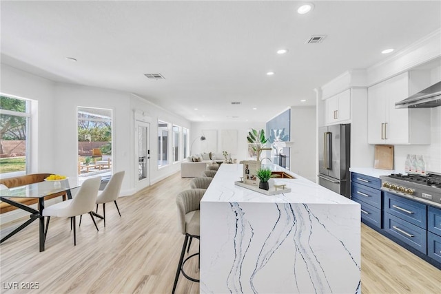 kitchen with high end refrigerator, visible vents, blue cabinetry, gas stovetop, and white cabinetry