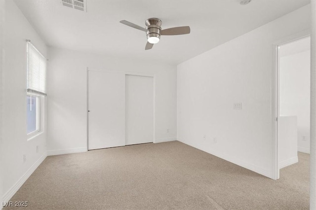 unfurnished bedroom featuring light carpet, a closet, visible vents, and a ceiling fan