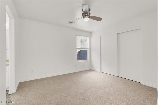 unfurnished bedroom featuring ceiling fan, light carpet, visible vents, baseboards, and a closet