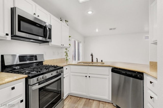 kitchen featuring white cabinets, appliances with stainless steel finishes, light countertops, and a sink