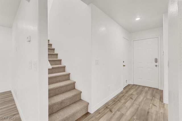 hall featuring light wood-type flooring, stairway, baseboards, and recessed lighting