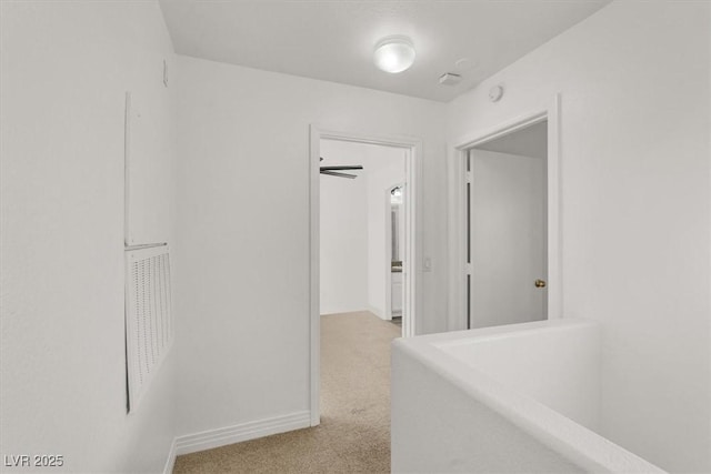 hallway featuring light carpet and baseboards