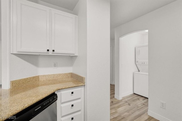 kitchen with stacked washer and dryer, light wood-type flooring, white cabinetry, and stainless steel dishwasher