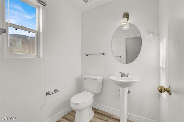 half bathroom featuring baseboards, toilet, and wood finished floors