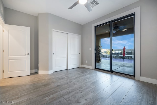 unfurnished bedroom featuring baseboards, visible vents, wood finished floors, access to outside, and a closet