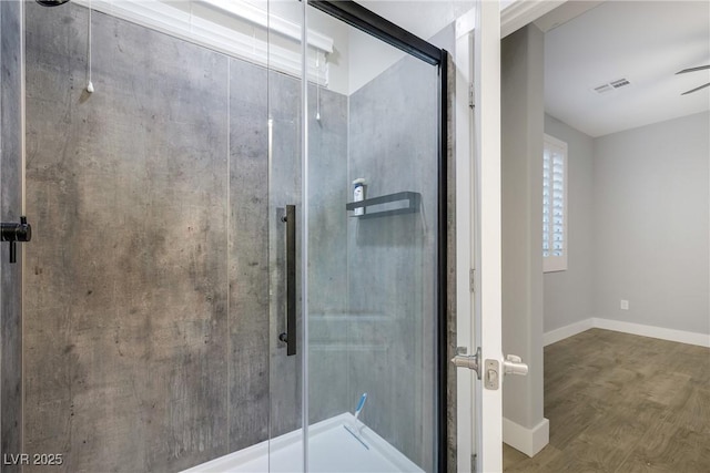 bathroom with baseboards, wood finished floors, visible vents, and a shower stall