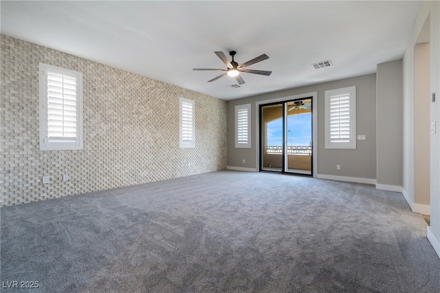 carpeted spare room featuring wallpapered walls, ceiling fan, visible vents, and baseboards