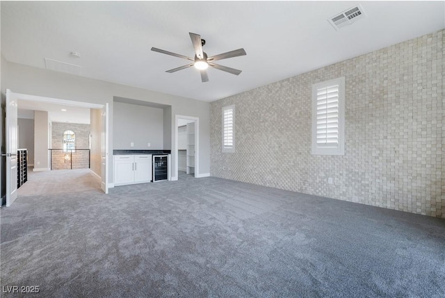 unfurnished living room featuring carpet, wine cooler, visible vents, and ceiling fan