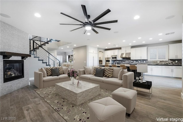 living area featuring stairway, light wood-type flooring, visible vents, and recessed lighting