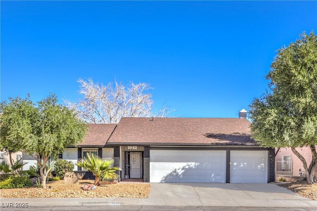 single story home featuring a garage, concrete driveway, and a chimney