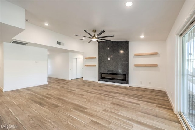 unfurnished living room featuring a ceiling fan, visible vents, a fireplace, and light wood-style flooring