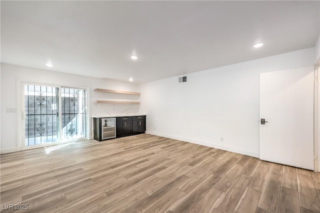 unfurnished living room with recessed lighting, visible vents, light wood-style flooring, beverage cooler, and baseboards