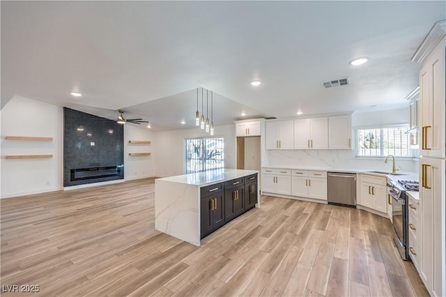 kitchen featuring stainless steel appliances, visible vents, white cabinets, open floor plan, and decorative light fixtures