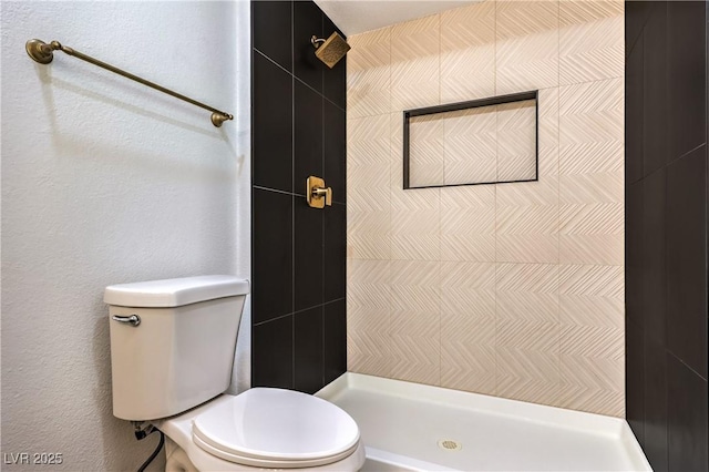 full bath featuring tiled shower, a textured wall, and toilet