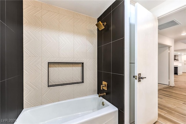 bathroom with wood finished floors, visible vents, and tub / shower combination