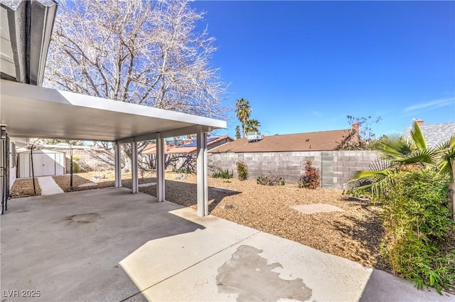 view of patio / terrace with fence, an outdoor structure, and a shed