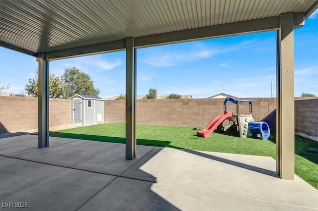 view of patio / terrace featuring an outbuilding, a shed, a playground, and a fenced backyard