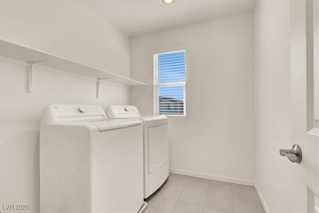 clothes washing area featuring laundry area, baseboards, washing machine and clothes dryer, and light tile patterned flooring