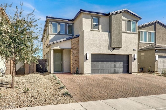 view of front of home featuring a garage, fence, decorative driveway, and stucco siding