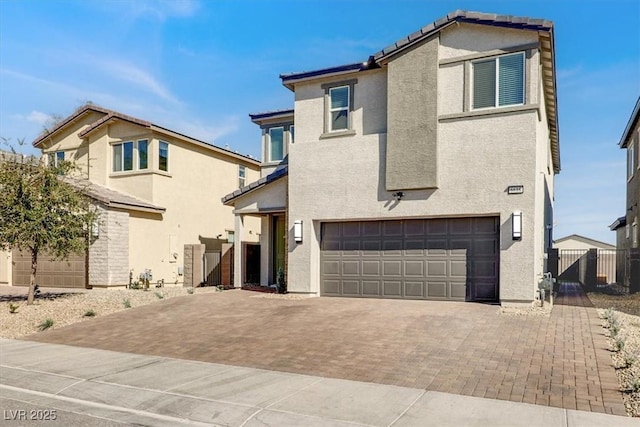 view of front of property featuring decorative driveway, fence, an attached garage, and stucco siding